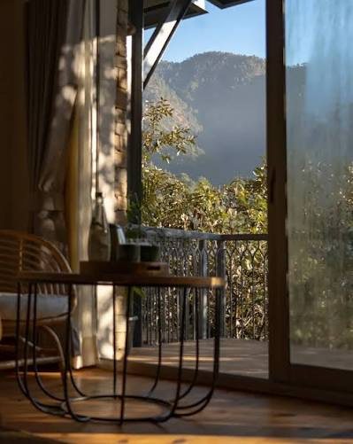 Sunlit balcony of a hill cottage looking out at a forested mountain